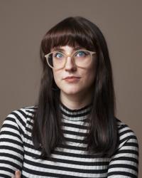 Laura Thomas in a striped shirt with a gray background.