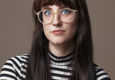 Laura Thomas in a striped shirt with a gray background.