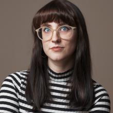 Laura Thomas in a striped shirt with a gray background.